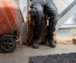 male sitting on bricks on construction site with chain round ankle