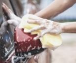 Man washing red car with sponge and soap