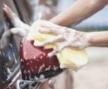 a close up of a man washing a car with a soapy sponge