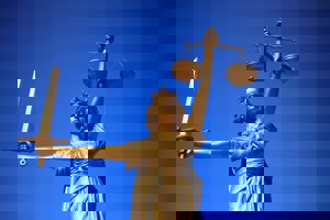 A bronze statue of Lady Justice with a blindfold, a beam balance, and a sword