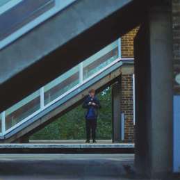 a vulnerable young person stood alone next to a building