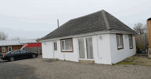 White bungalow with black car to the left