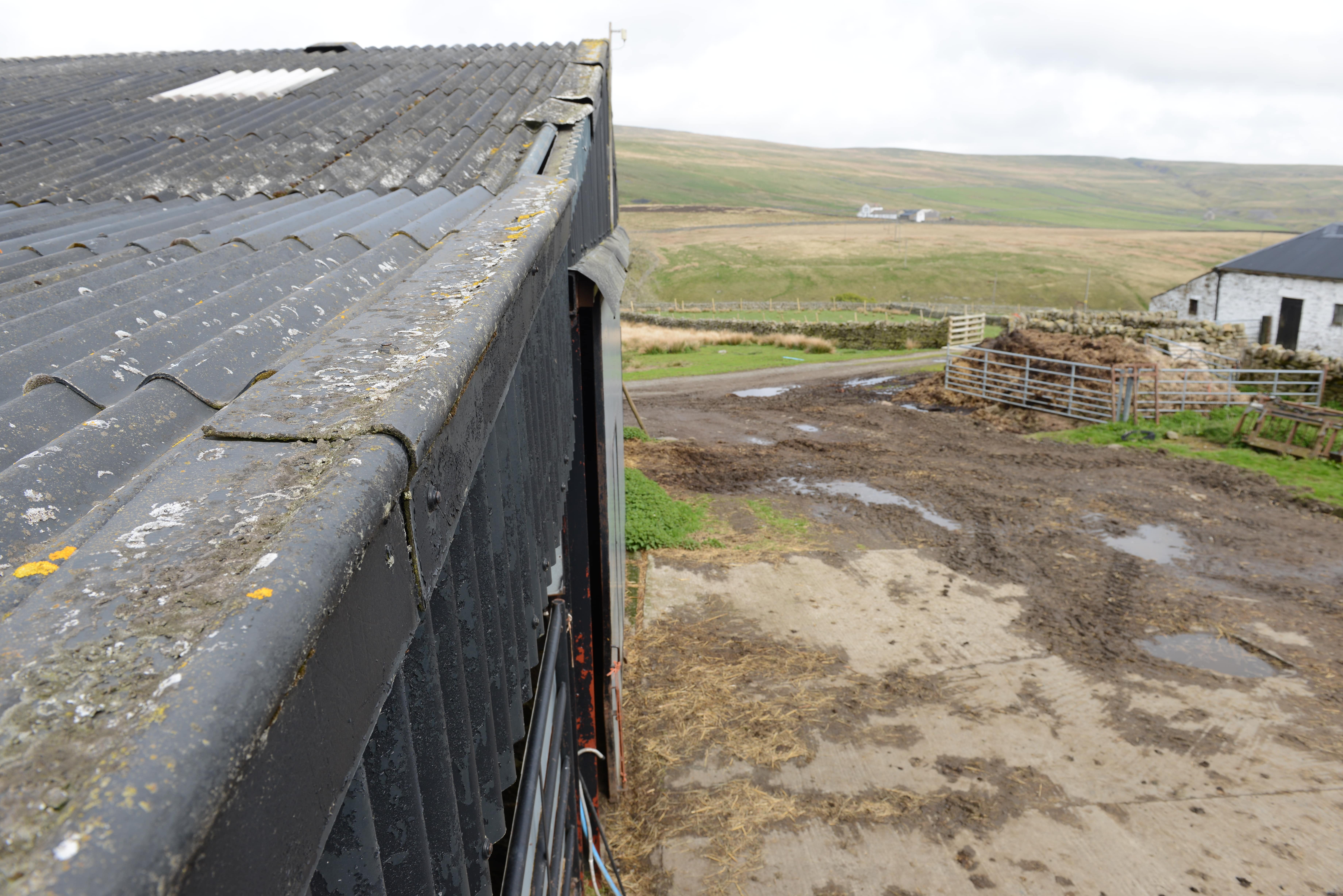 Top of the barn roof looking across a farm yard with fields in the distance