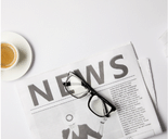 spectacles on newspaper with word news and cup of coffee