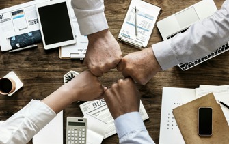 four people's fists together donating good team work