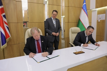 Darryl Dixon signing the document in Uzbekistan