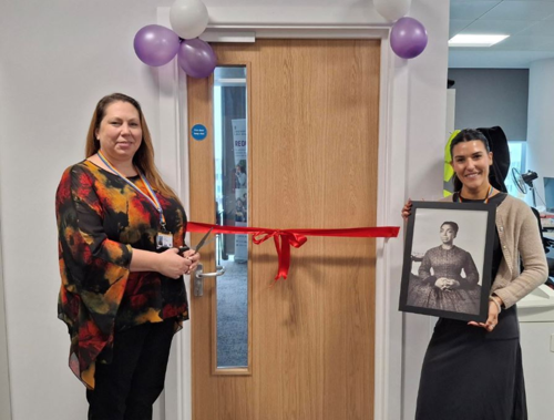 Two women either side of a door cutting red ribbon